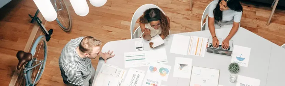 A team working around a table covered with charts, seen from above.