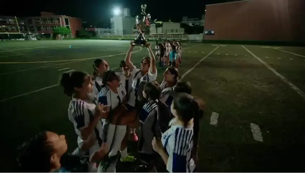 A girls’ football team lifting a teammate after a match